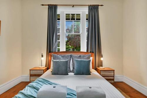 a bedroom with a bed with blue pillows and a window at Edwina Suite I - Sleek and Stylish CBD Wi-Fi in Orange