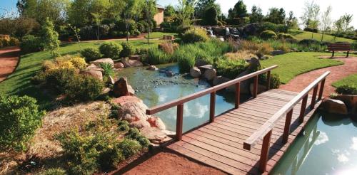 a wooden bridge over a pond in a garden at Sterling House Spacious Deck BBQ Pet Friendly in Dubbo