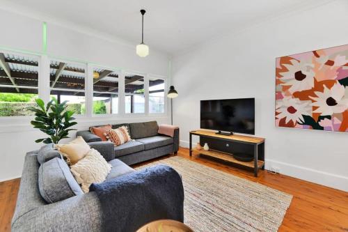 a living room with a couch and a tv at Oasis on Warrendine, Sleek & Stylish, Free Wi-Fi in Orange