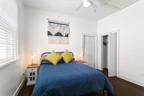 a bedroom with a bed with blue sheets and yellow pillows at Stylish Creole Cottage 1 BD Home Central Location in New Orleans