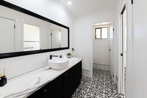 Baño blanco con lavabo y espejo en Aspen Abode - CBD, Fireplace, BBQ, 3 Smart TVs en Dubbo
