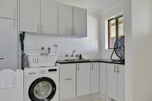 a white kitchen with a washing machine and a sink at Narambla Estate - Rural Retreat, Luxe Hideaway in Orange