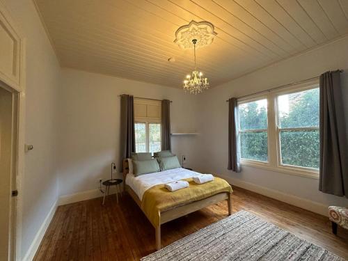 a bedroom with a bed and a chandelier at Bultje Cottage - Walk to CBD, Pet Friendly in Dubbo