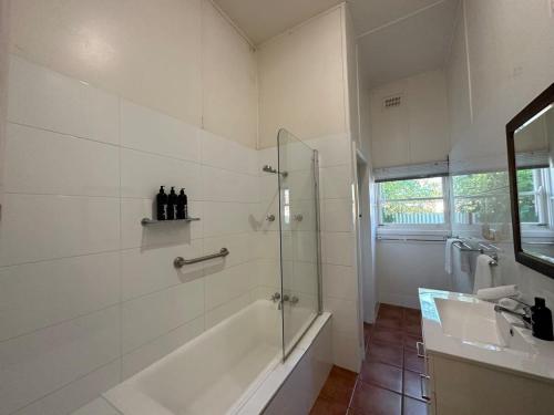a white bathroom with a shower and a sink at Bultje Cottage - Walk to CBD, Pet Friendly in Dubbo