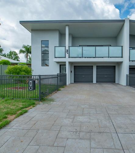 a house with two garage doors and a driveway at Cosy Retreat on Naman - Private & Convenient in Dubbo