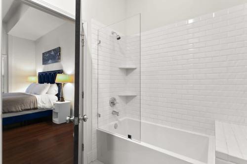 Cette chambre comprend un lit et une salle de bains pourvue d'une douche. dans l'établissement Modern pristine stunning 2BD Garden District Apt, à La Nouvelle-Orléans