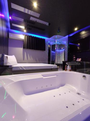 a large white bath tub in a room with purple lights at Prestige Motel 2 in Sorocaba