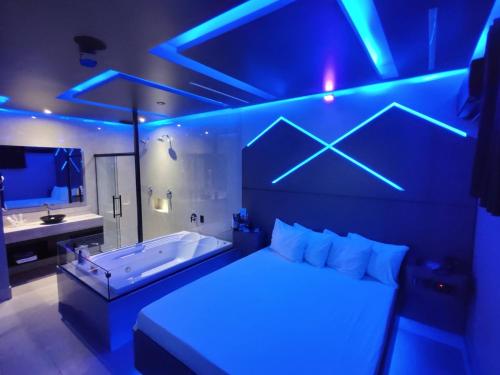 a bedroom with a tub and a bathroom with blue lights at Prestige Motel 2 in Sorocaba