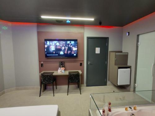Prestige Motel 2 في سوروكابا: غرفة مع تلفزيون على جدار مع طاولة وكراسي