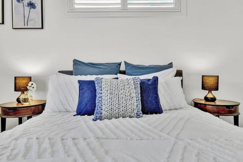 a bedroom with a white bed with blue pillows at The Entertainer - 5 Bed 5 Bath, 3 Storey Retreat in Orange