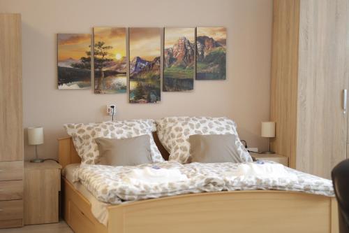 佩奇的住宿－Stardust apartman，卧室配有一张壁挂着四幅画作的床