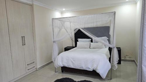 1 dormitorio con 1 cama blanca con dosel en Artem Apartments - Apartment 3, en Kitwe