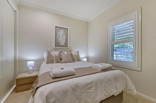a white bedroom with a large bed and a window at The Sampson Haven - Luxe CBD Getaway, Dog Friendly in Orange