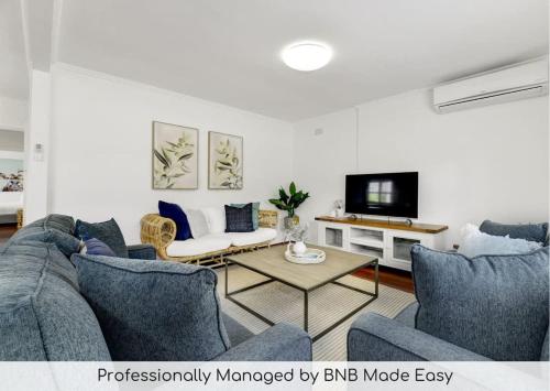 a living room with a couch and a tv at Hope St Cottage - Elegant & Cosy, Sleeps 6 in Bathurst