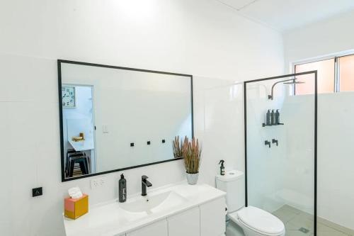a bathroom with a sink and a toilet and a mirror at Tamworth Retreat - Sleek & Stylish, Sleeps 5 in Dubbo