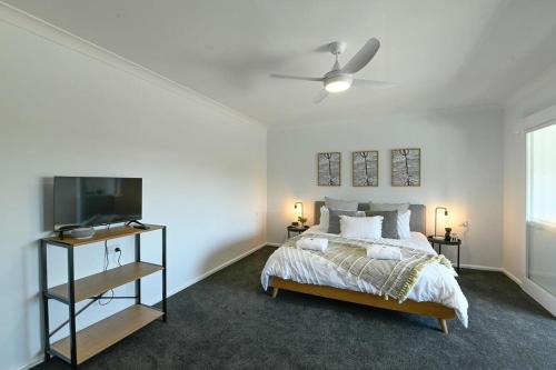 a bedroom with a bed and a flat screen tv at Tamworth Retreat - Sleek & Stylish, Sleeps 5 in Dubbo