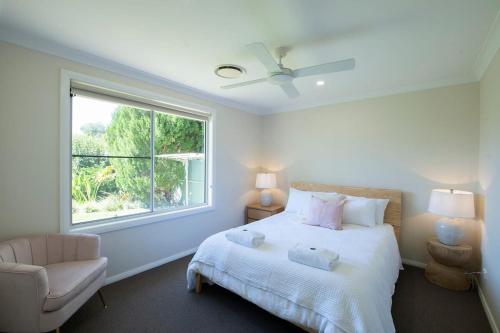 a white bedroom with a bed and a window at Regand Retreat - Pool, Luxurious Family Home in Dubbo