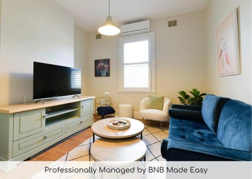 a living room with a blue couch and a tv at Hope St Cottage I - Historic Haven, Mountain Views in Bathurst