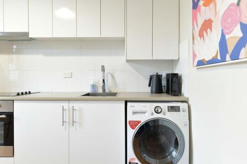 a white kitchen with a washing machine in it at Hope St Cottage I - Historic Haven, Mountain Views in Bathurst
