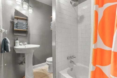 an orange shower curtain in a bathroom with a sink at Gorgeous backyard Pool 2BD Midcity Retreat in New Orleans