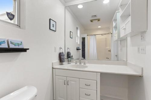 a white bathroom with a sink and a mirror at 4BD Metairie retreat with driveway and yard in Metairie