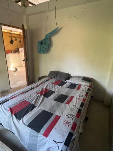 a bed in a room with a quilt on the wall at Casita con linda jardín a 1minutos de la playa in Las Tunas
