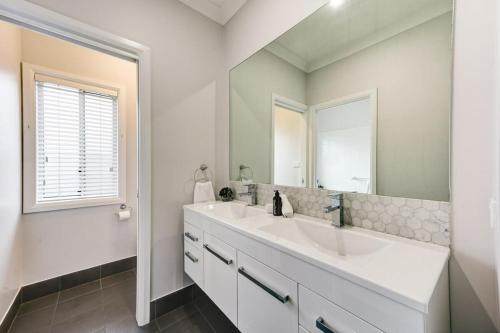 uma casa de banho branca com um lavatório e um espelho em Serenity on Severn - Exquisite Family Home, 3 TVs em Dubbo