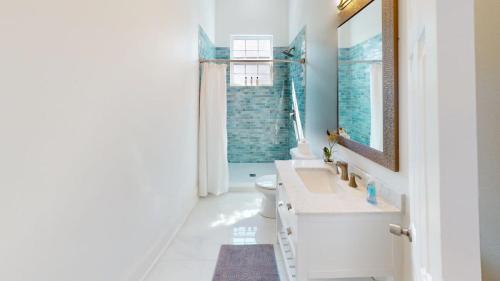 a white bathroom with a sink and a mirror at Sunny 5Bed w Parking and direct Streetcar access in New Orleans