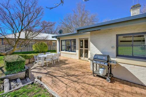 a barbecue on a brick patio in front of a house at Heritage Charm on Hill - Tree-Lined Walk to Town in Orange