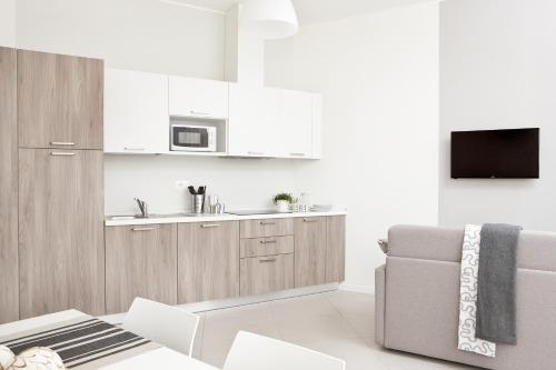 a white kitchen with a couch and a microwave at Palazzo Talenti 1907 in Trieste