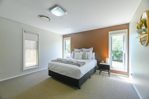 a bedroom with a large bed and two windows at Southlakes Haven - Lake Views, Pet Friendly in Dubbo