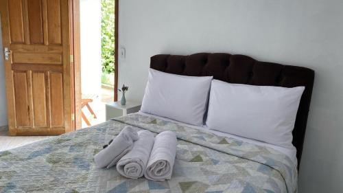 a bed with three pairs of towels on it at Chalés Família Onofre in Divisa