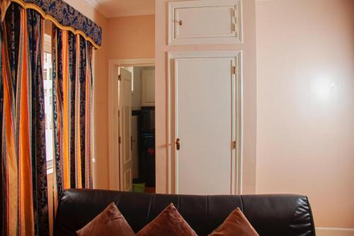 ein schwarzes Ledersofa im Wohnzimmer mit Tür in der Unterkunft Studio 110 in Luanda