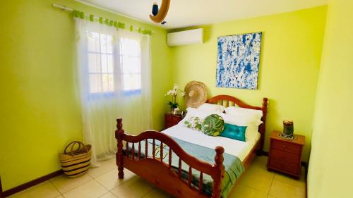 een slaapkamer met een bed met groene muren en een raam bij Maison de rêve avec piscine et jacuzzi aux portes de la forêt in Petit-Bourg
