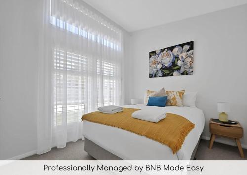 a white bedroom with a bed and a window at The Elm Apartments - The Yellow Room in Orange