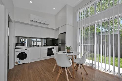 a kitchen with white cabinets and a table and chairs at The Elm Apartments - The Orange Room in Orange