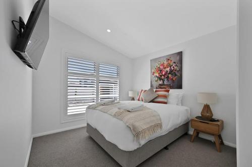 a white bedroom with a large bed and a window at The Elm Apartments - The Orange Room in Orange