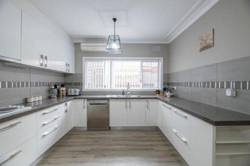 a large kitchen with white cabinets and a window at Roycox Cottage - Charming Escape, Fireplace in Dubbo