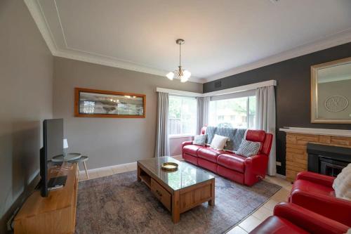 a living room with a red couch and a fireplace at Roycox Cottage - Charming Escape, Fireplace in Dubbo
