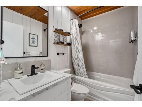 ein Badezimmer mit einem Waschbecken, einem WC und einem Spiegel in der Unterkunft Merlot Mountain I Ping Pong I Sleep 7 I 55 RokuTV in Invermere