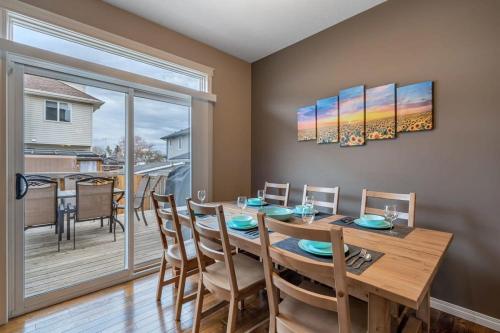 a dining room with a table and chairs and a balcony at Prairie Oasis I Sleeps 16 l BBQ & Patio l Smart TV in Sylvan Lake