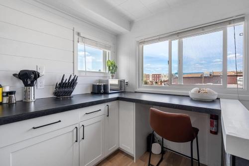 a kitchen with white cabinets and a black counter top at The Hidden Loft I 5-min Walk 2 Beach I DT I 55 TV in Sylvan Lake