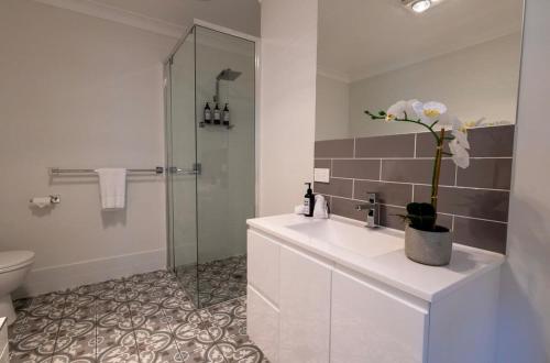 a white bathroom with a sink and a shower at The Hideaway - Close to Zoo & Golf Club in Dubbo