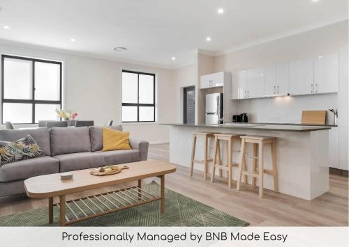 a living room with a gray couch and a kitchen at Crooked Lane Apartment - CBD, Stylish & Central in Wagga Wagga