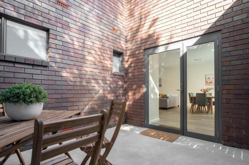 a wooden bench sitting next to a brick wall at Crooked Lane Apartment - CBD, Stylish & Central in Wagga Wagga