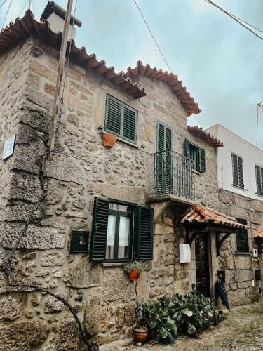 an old stone building with green shutters and a balcony at Cantinho de Aldeias in Gouveia