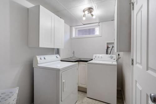 a white laundry room with two washes and a window at Bahama Breeze I Hot Tub I Pool I 5 Bedroom in Drumheller