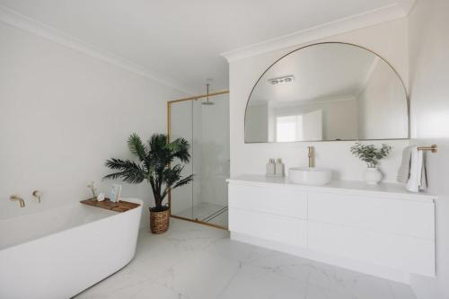 a white bathroom with a sink and a mirror at Macquarie - Sleek & Stylish, Countryside Views in Dubbo