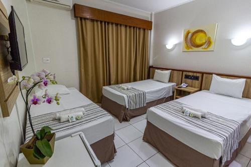 a hotel room with two beds and flowers in it at Hotel Nacional Inn Araçatuba in Araçatuba