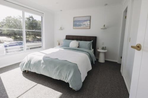 a white bedroom with a large bed and a window at Macquarie - Sleek & Stylish, Countryside Views in Dubbo